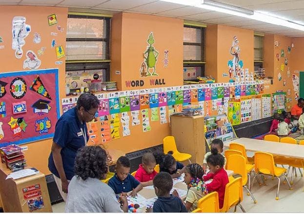 Adults and children in a classroom with a word wall