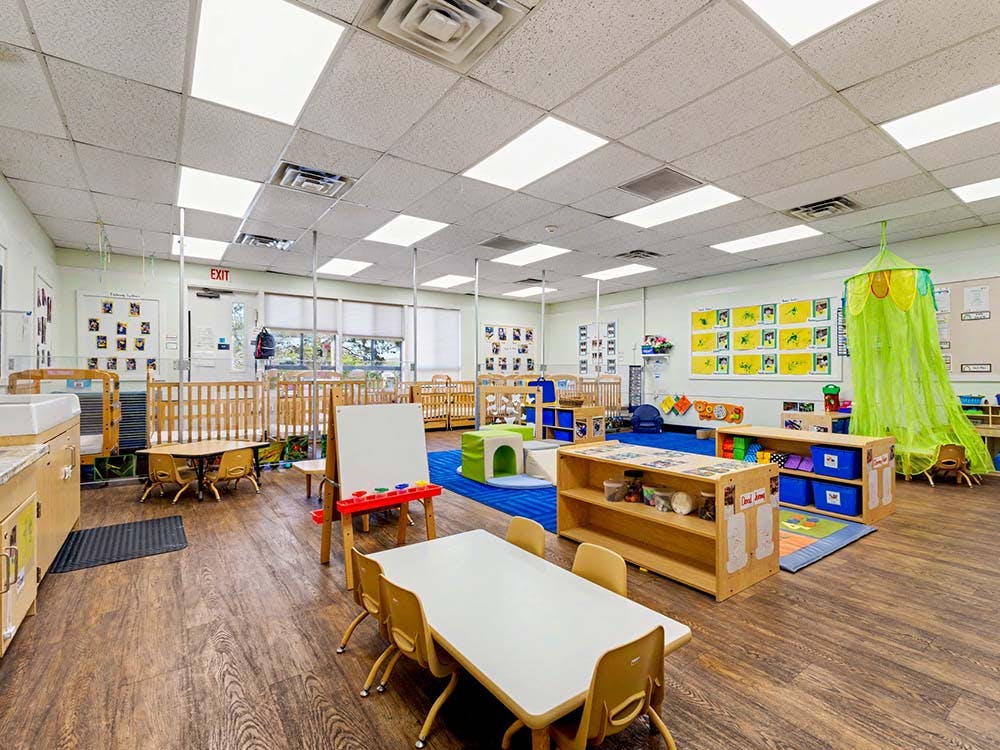 Empty preschool classroom with cribs and play areas