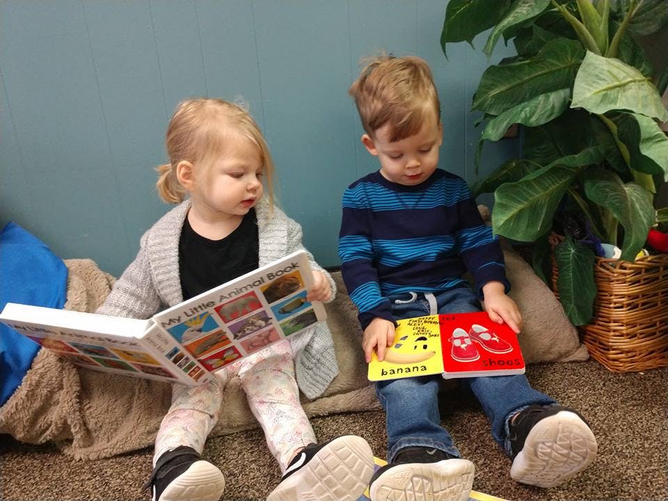 Two children sitting on the floor reading books