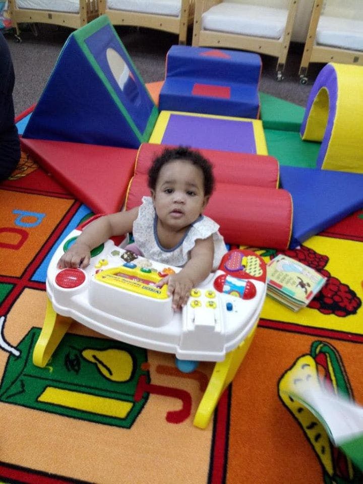 Child in a baby activity center on a colorful rug with soft play equipment