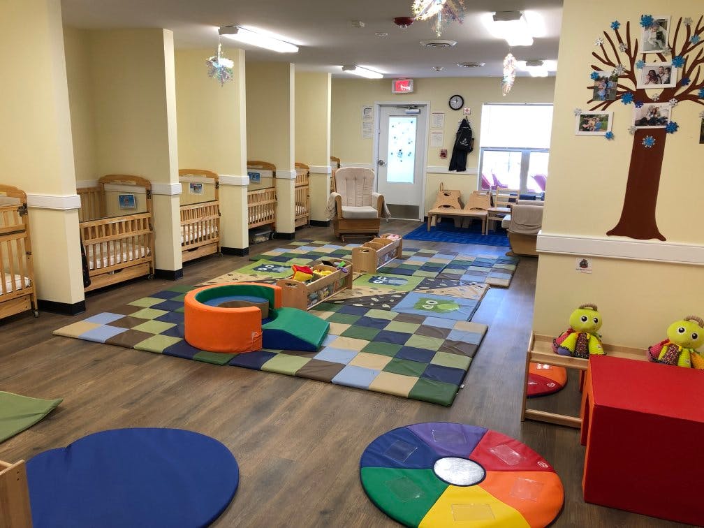 Cribs and play mats in a bright daycare room