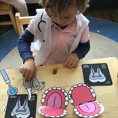 Child in a doctor's coat playing with dental-themed cutouts