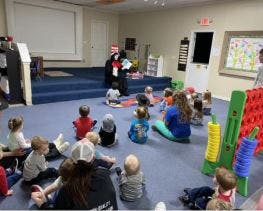 Person dressed as Cat in the Hat reading to children and adults