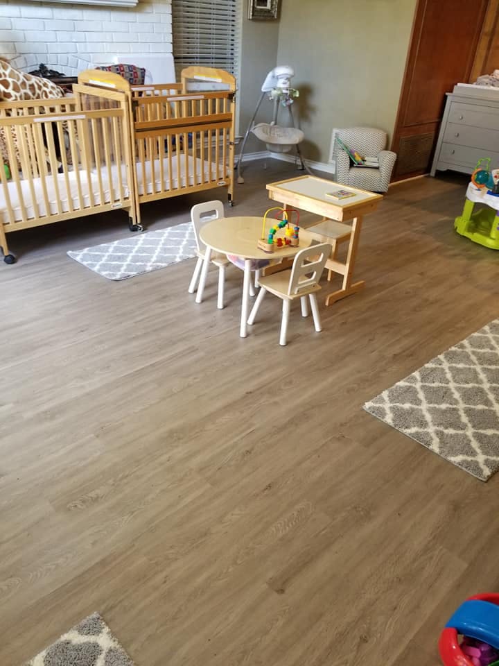 Two cribs, a child-sized table with chairs, and a high chair in a room