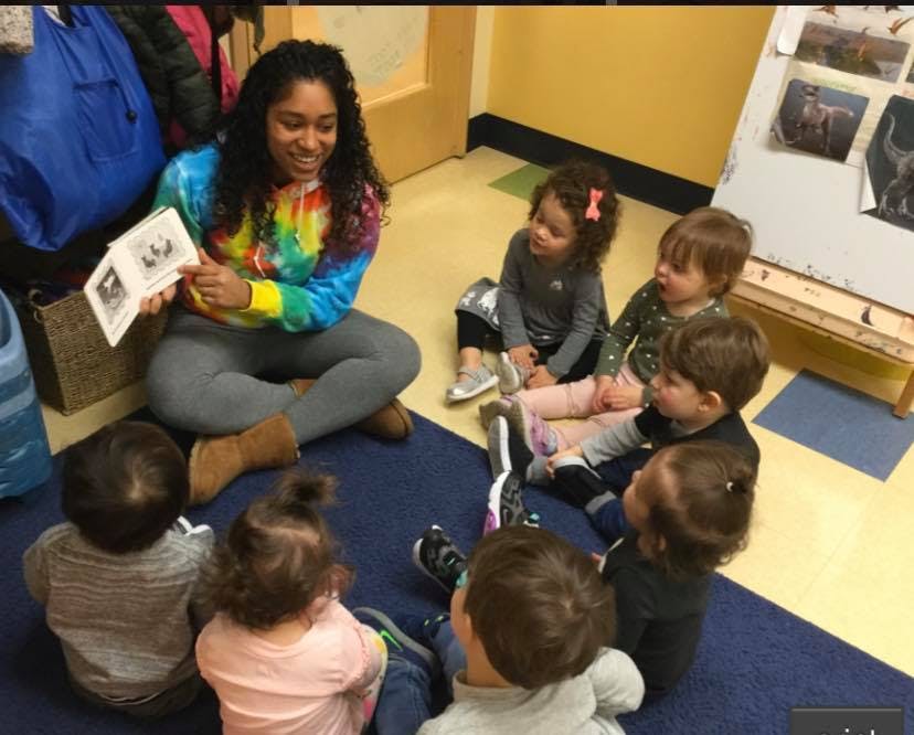 Person reading a book to a group of children in a classroom