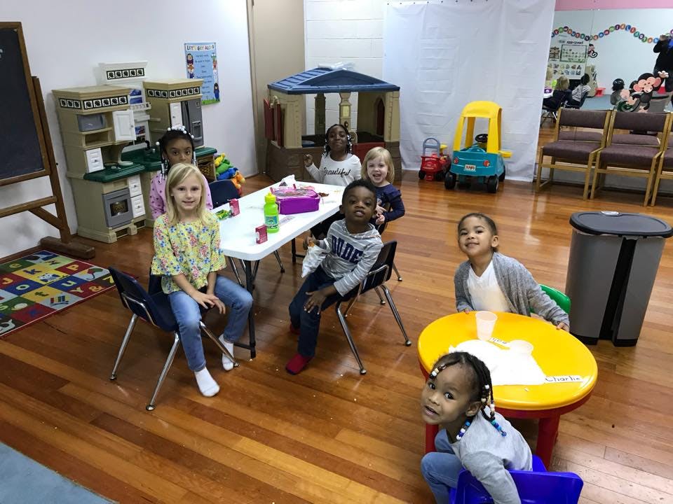 Multiple children sitting at tables in a classroom