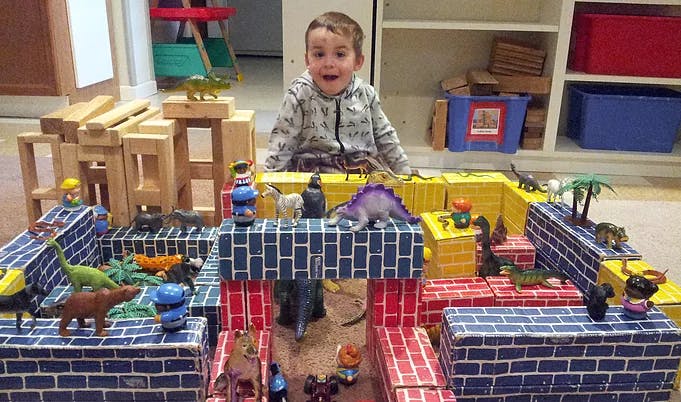 Child playing with toy dinosaurs and blocks