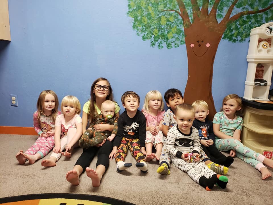 Group of children and a teen sitting on the floor in a room