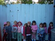 Group of children standing in front of a fence