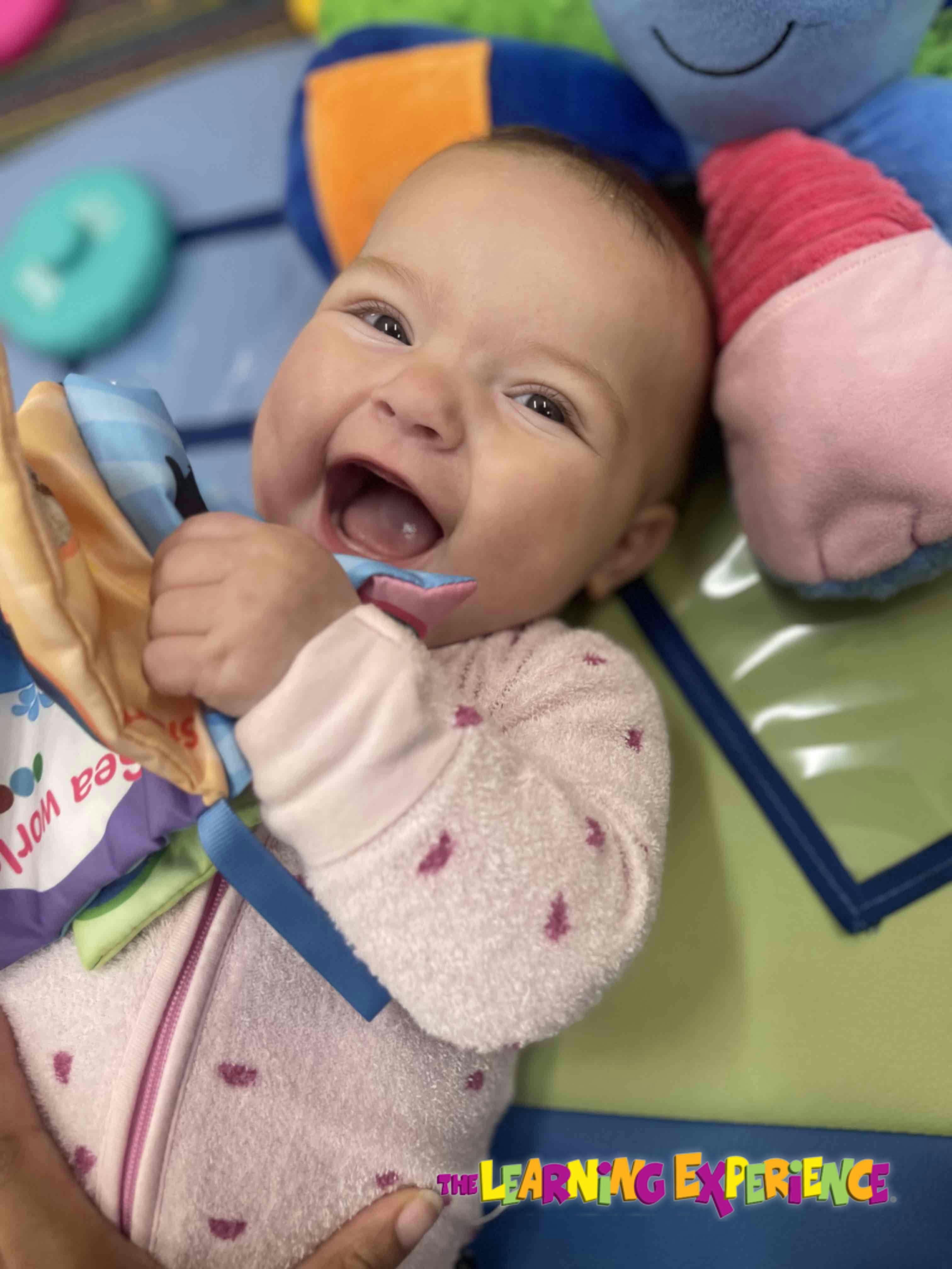 Child laughing and holding a soft toy