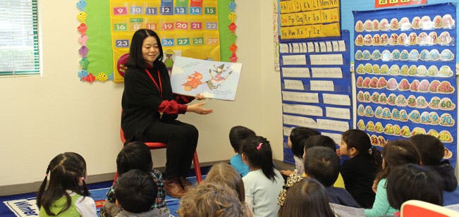Person reading a book to children in a classroom