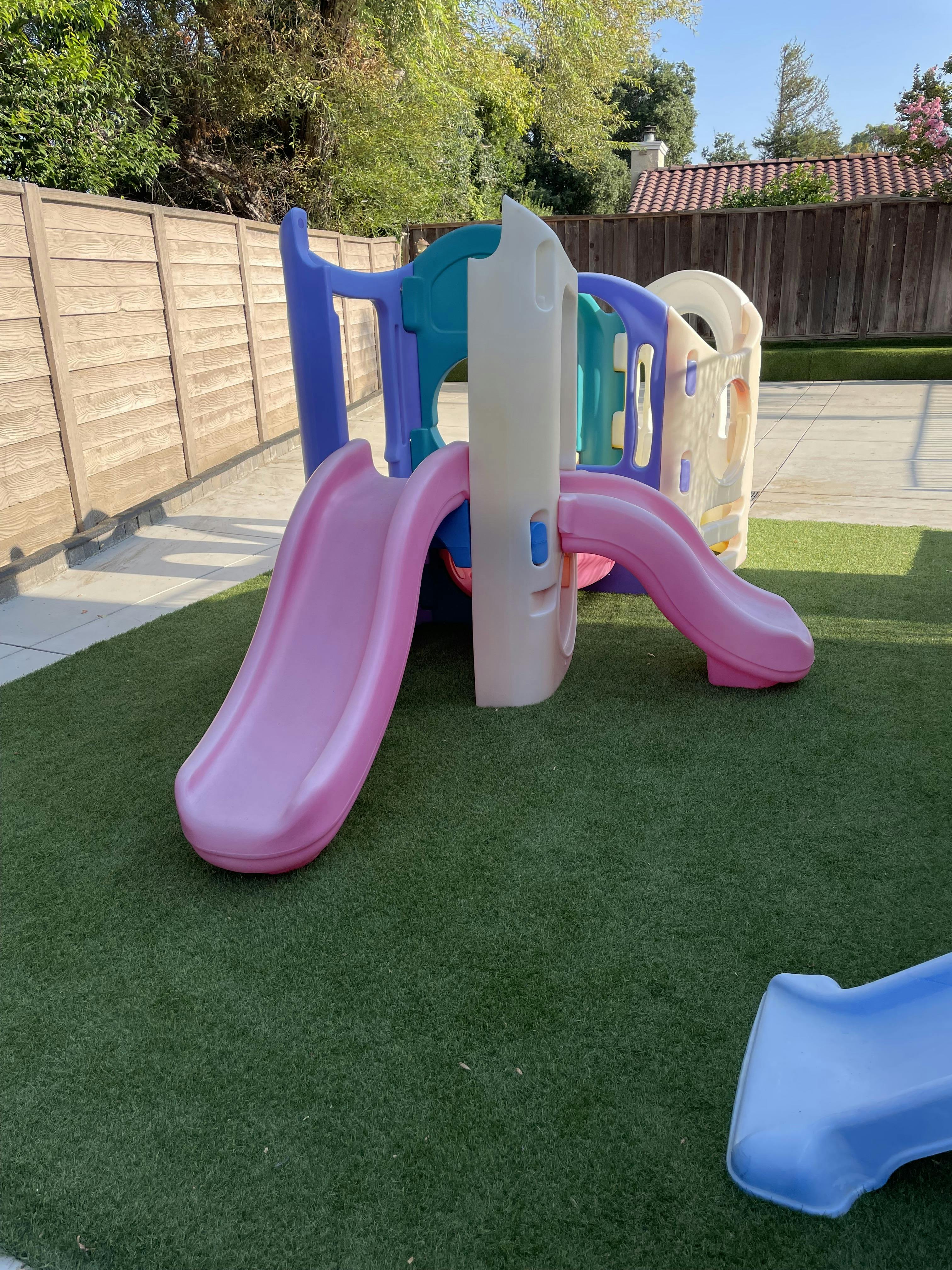 Plastic playground structure with two slides on artificial grass
