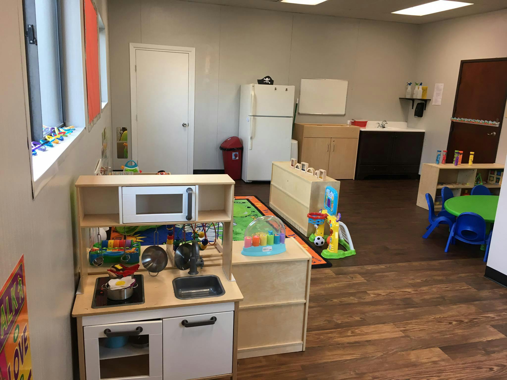 Playroom with toy kitchen, refrigerator, and small table with chairs