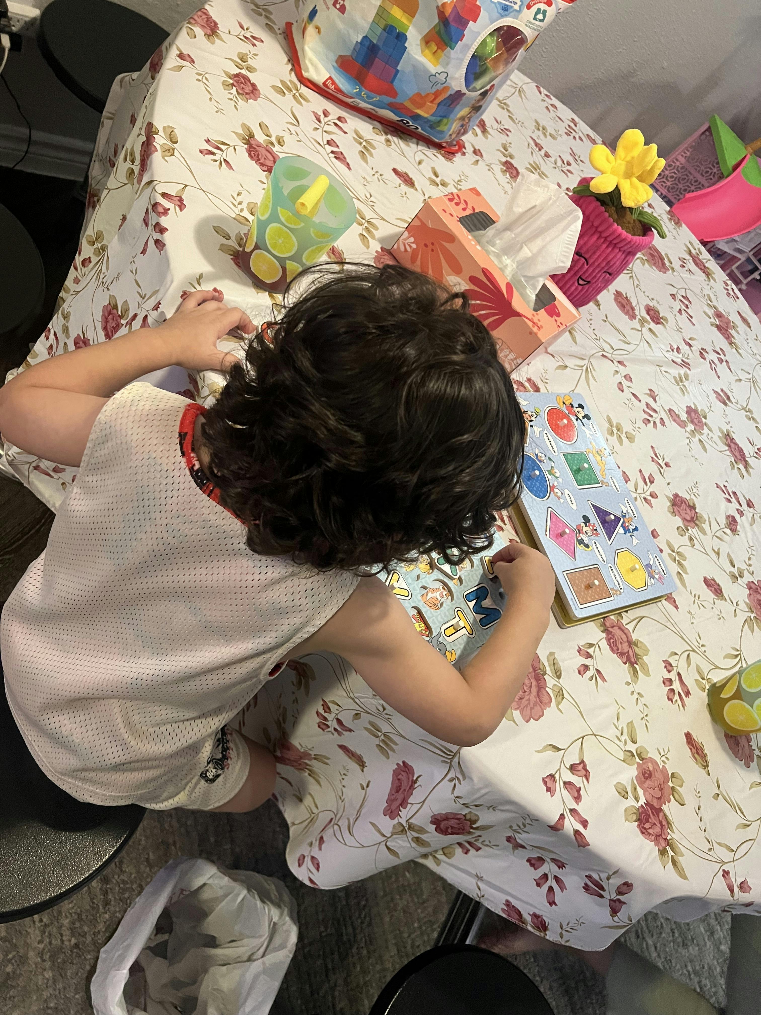 Child playing with a shape puzzle at a table