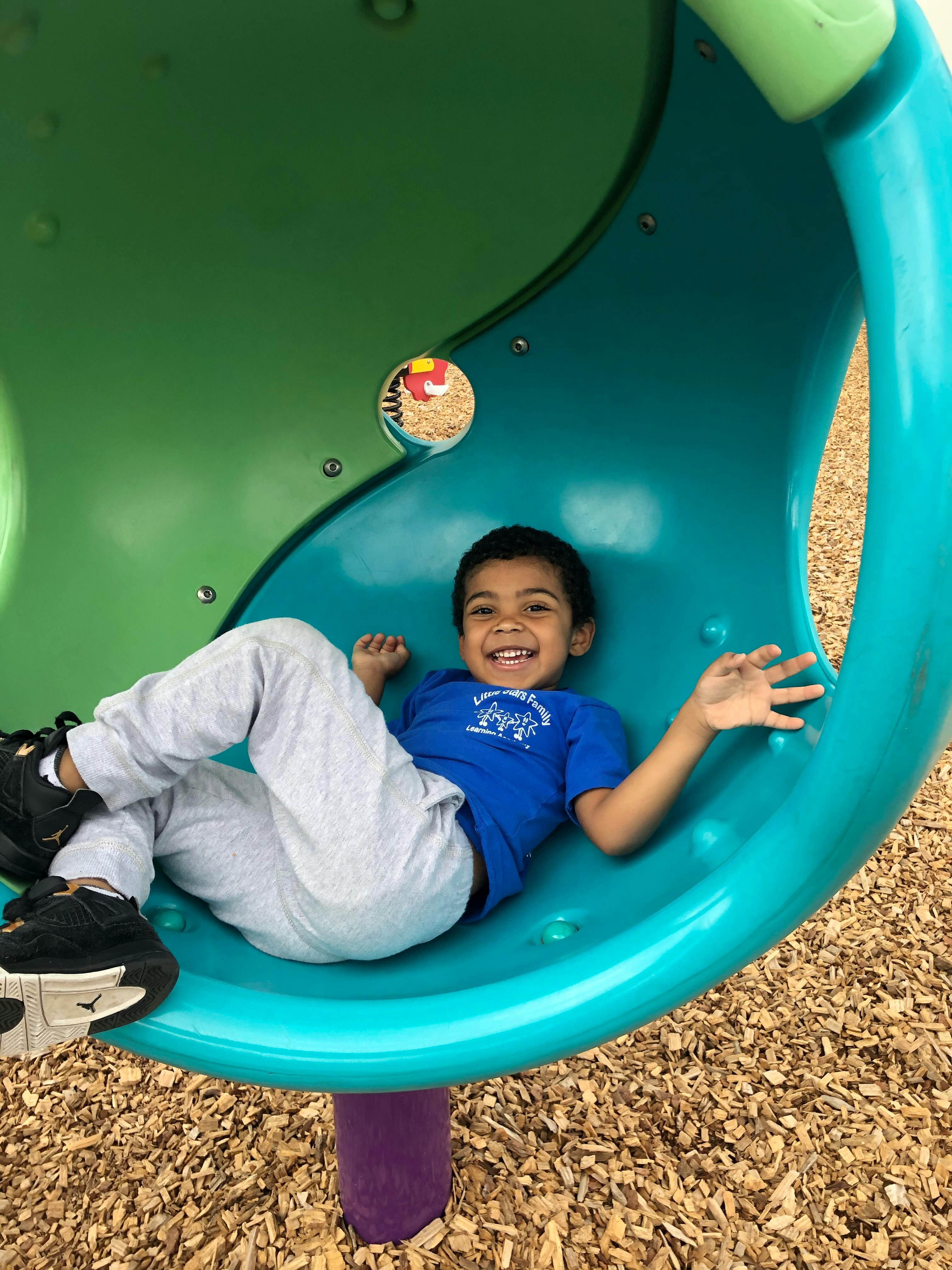 Child lying in a blue and green playground structure