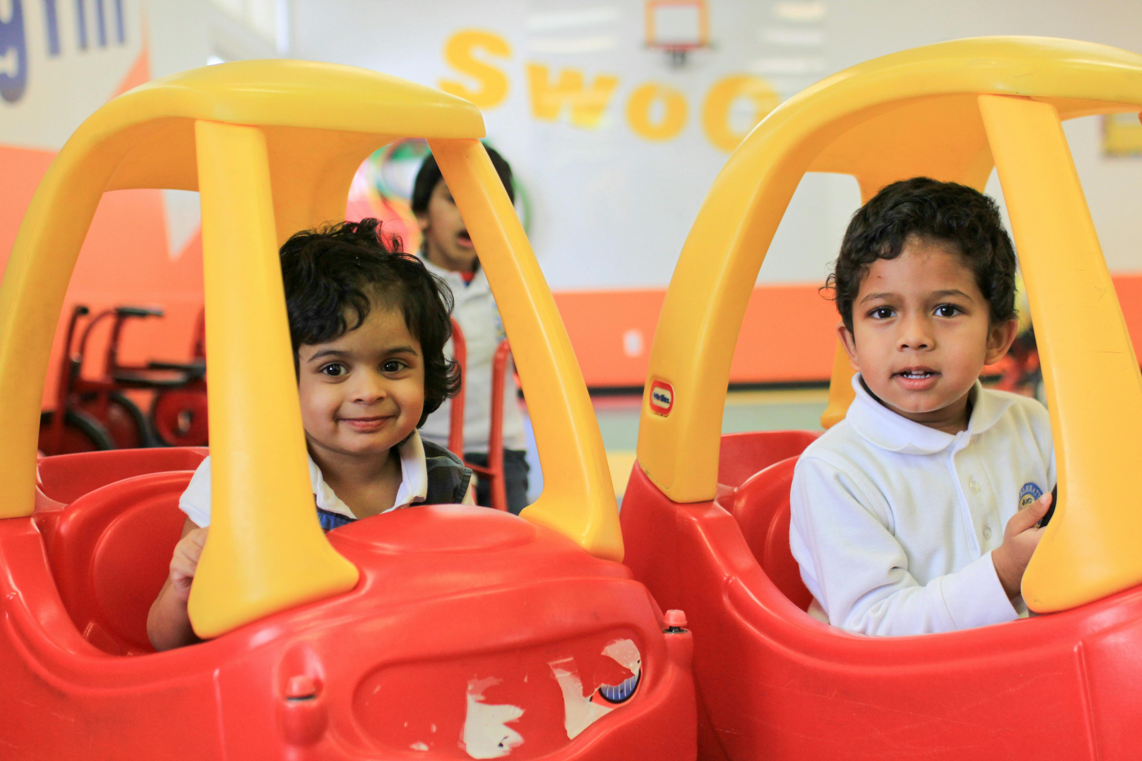 Two children sitting in toy cars