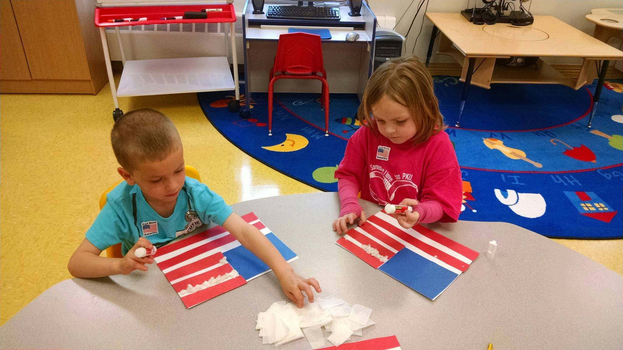 Two children making flag crafts at a table