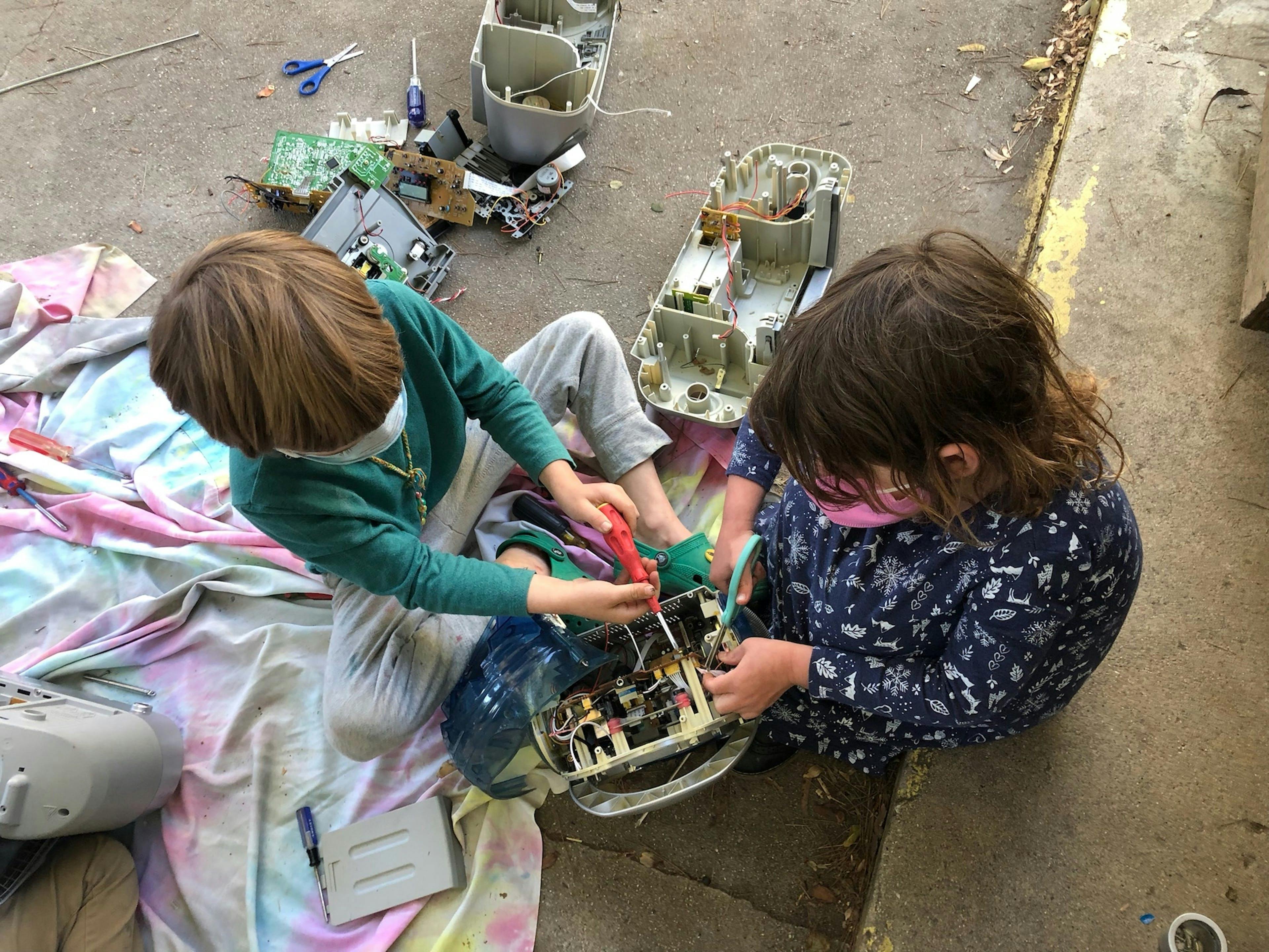 Two children working on electronics with tools