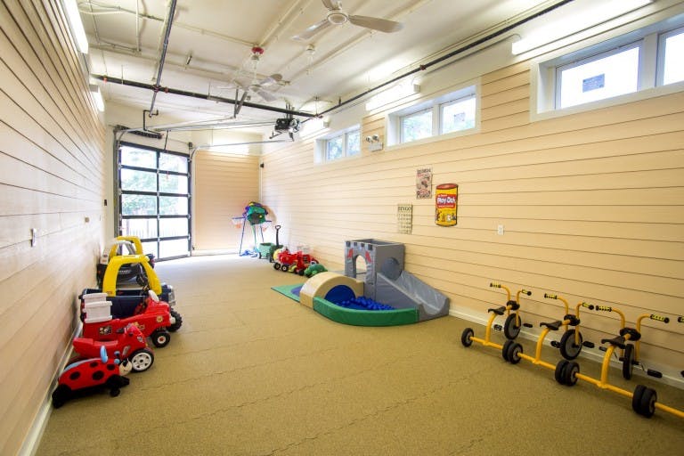 Indoor play area with ride-on toys and a small slide with a ball pit