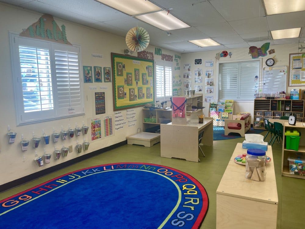 Empty classroom with small tables, chairs, and learning materials