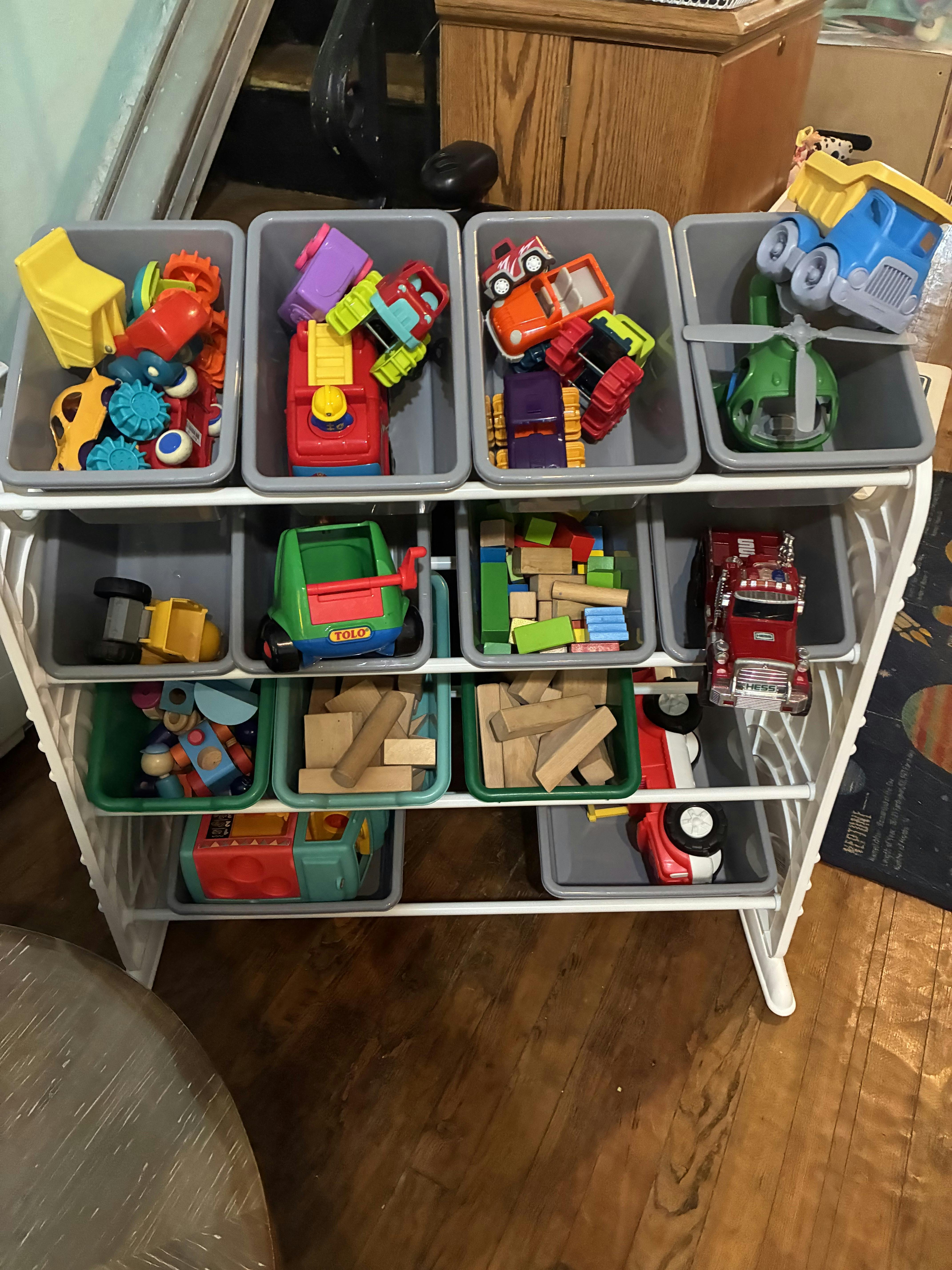 Toy storage unit with bins full of various toys