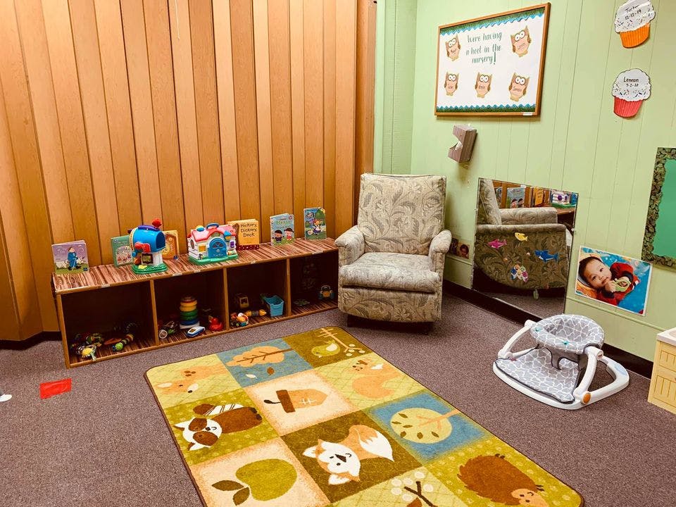 Playroom with a rug, toy shelf, two armchairs, and a baby walker