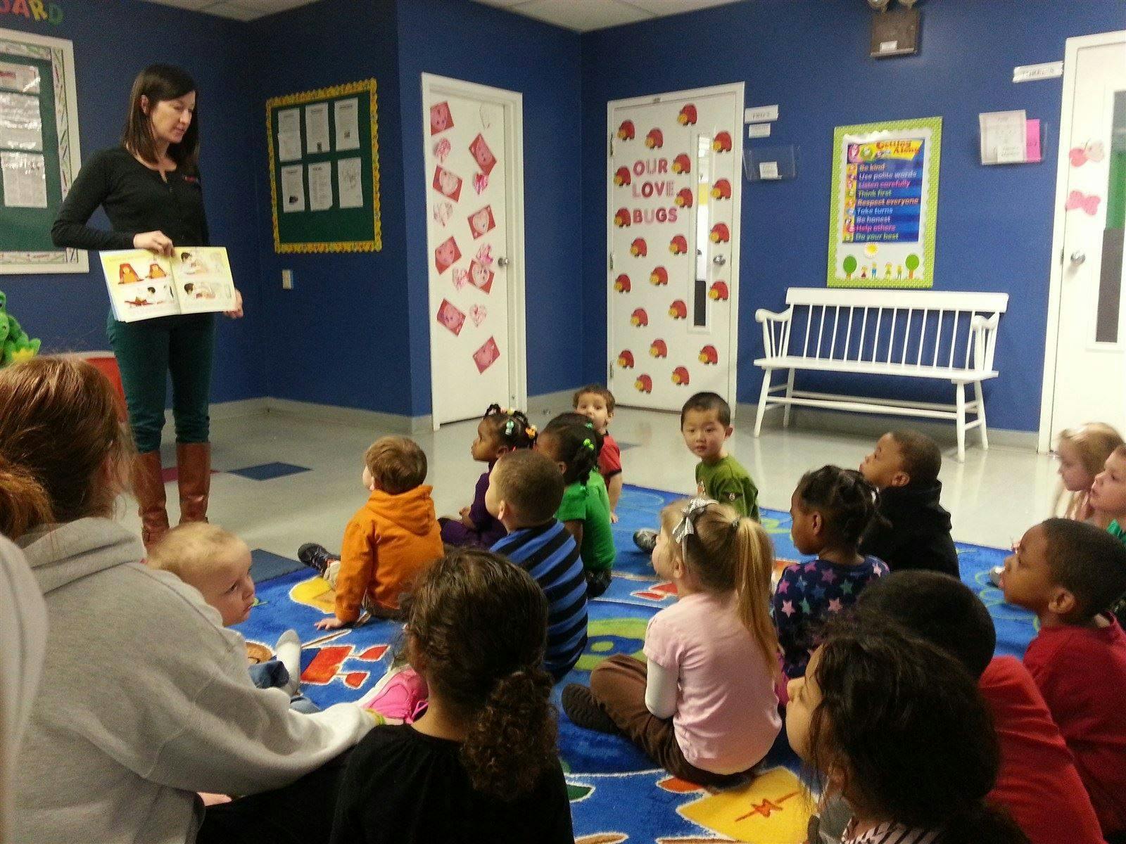 Person reading a book to a group of children in a classroom