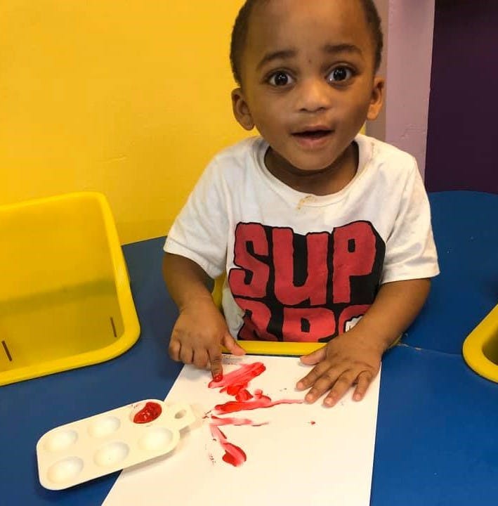 Child finger painting with red paint on paper