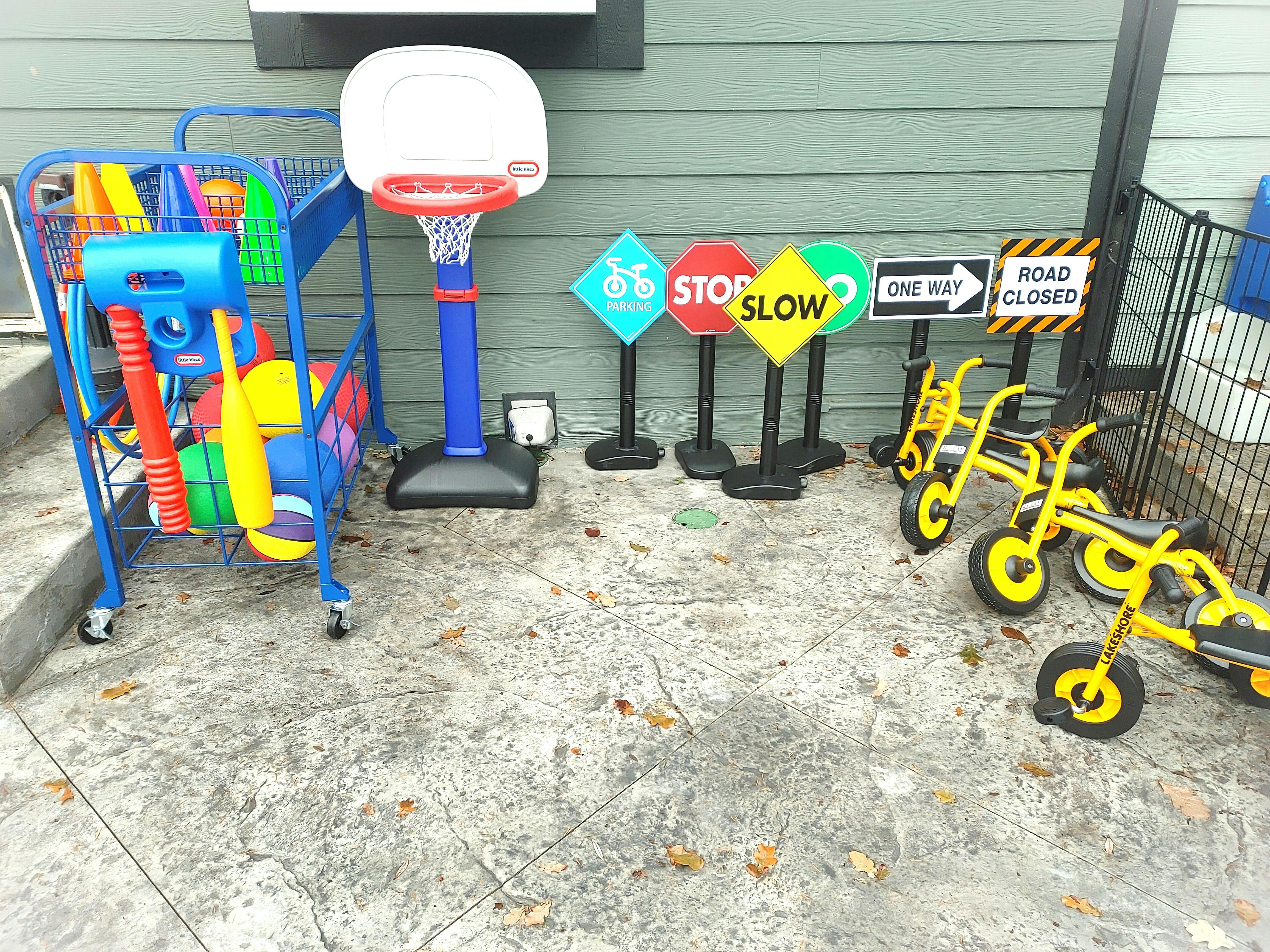 Playground equipment including a toy cart, basketball hoop, and small tricycles