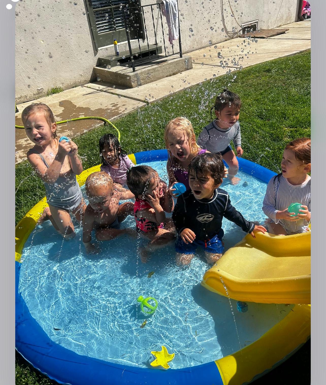 Children playing in a small inflatable pool with water spraying