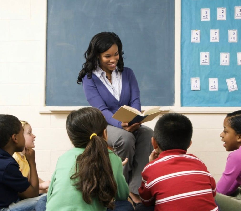 Person reading a book to children in a classroom