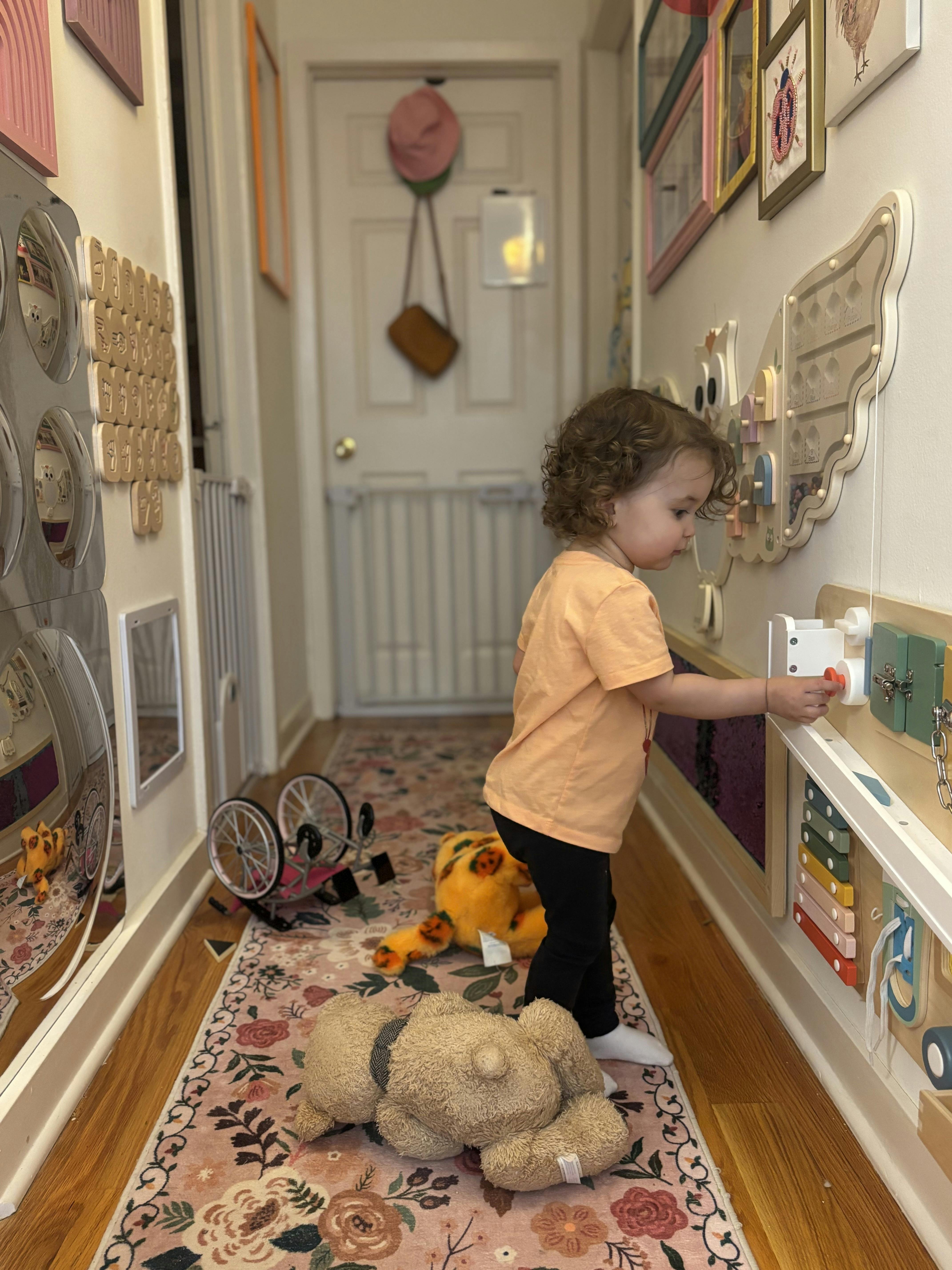 Child playing with a busy board in a hallway