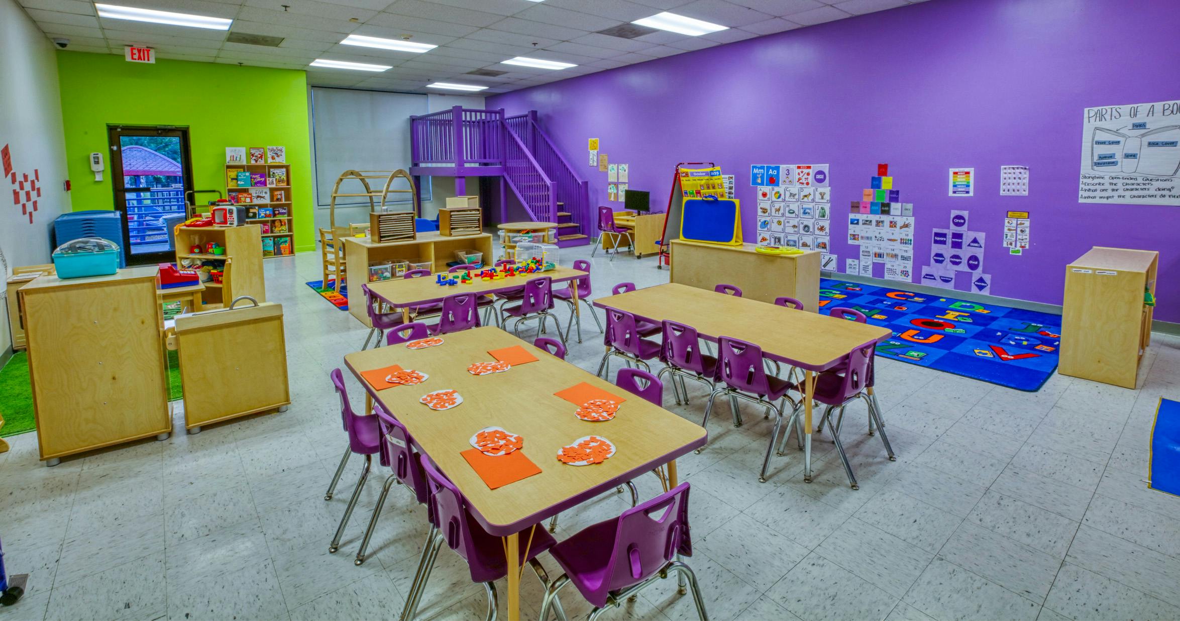 A colorful classroom with tables, chairs, and learning materials