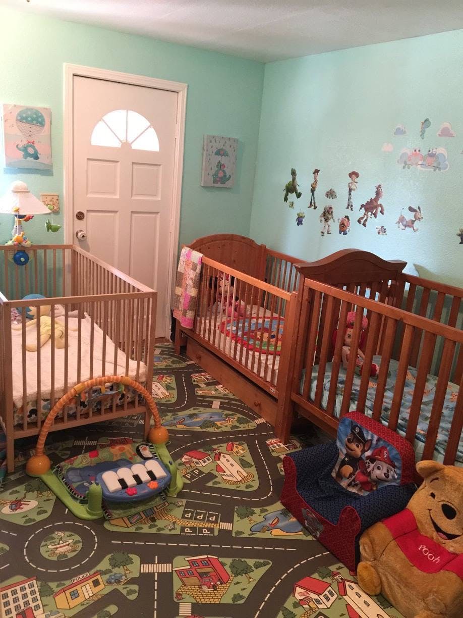 Two wooden cribs in a room with a road map rug