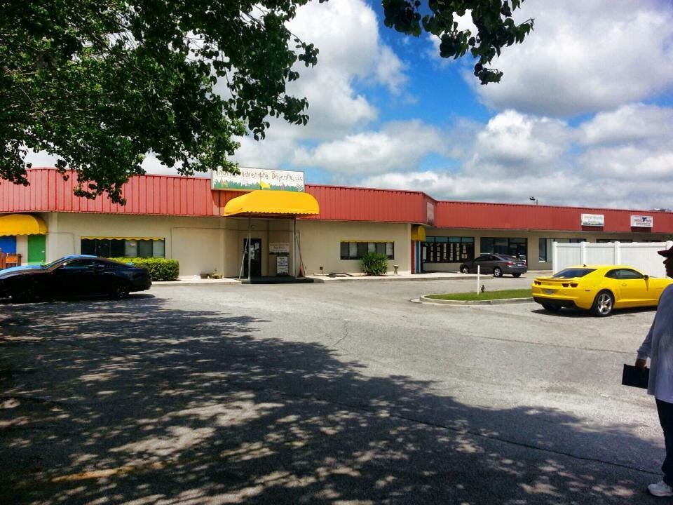 Building with red roof and yellow awning, with cars in a parking lot