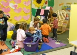 Adult and children playing with toys in a classroom