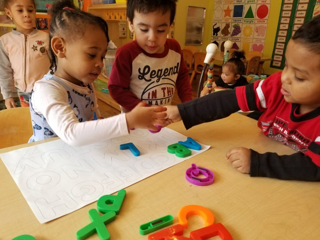 Children playing with colorful letter and number shapes on a table