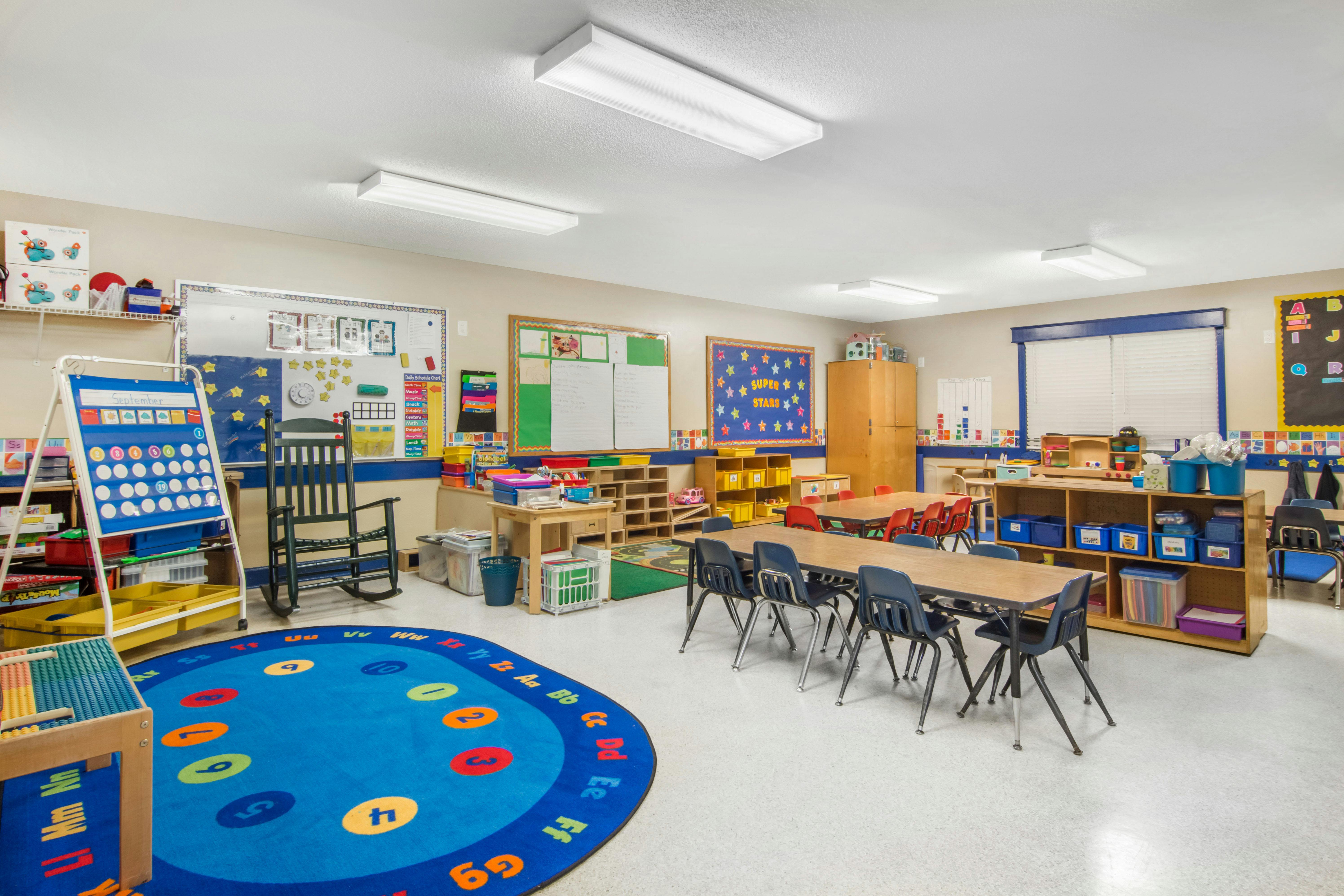 A colorful empty classroom with a large blue alphabet rug