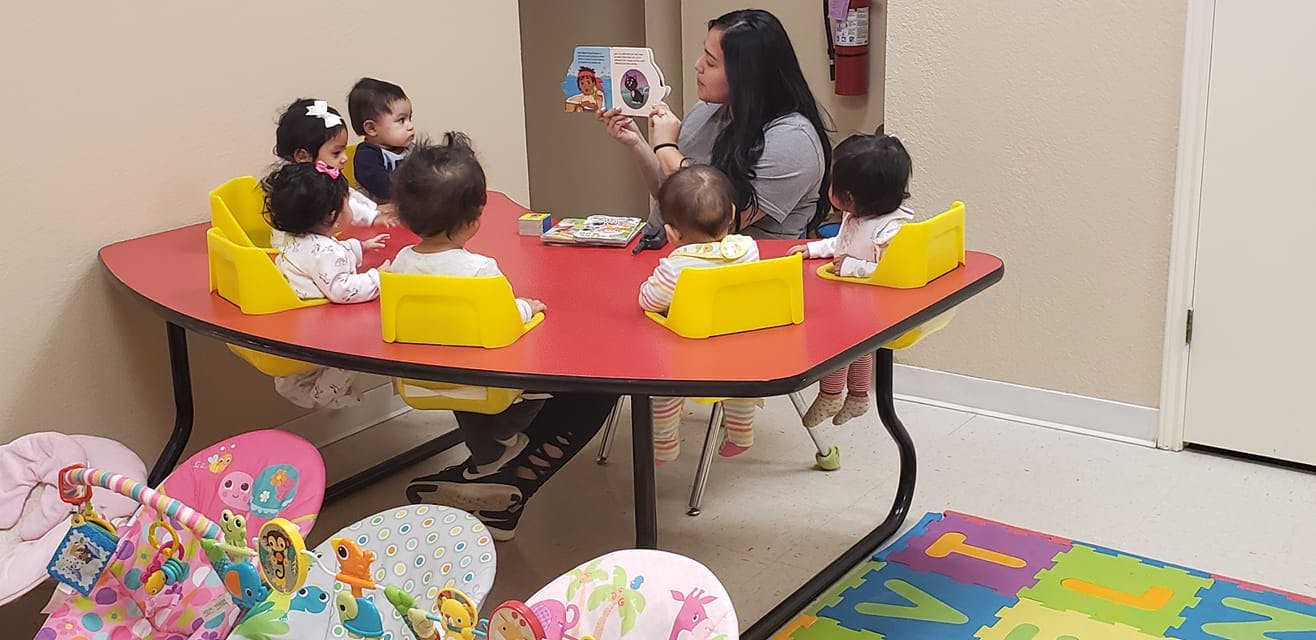Person reading a book to several children at a table