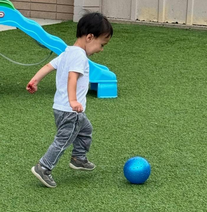 Child running to kick a ball on artificial grass