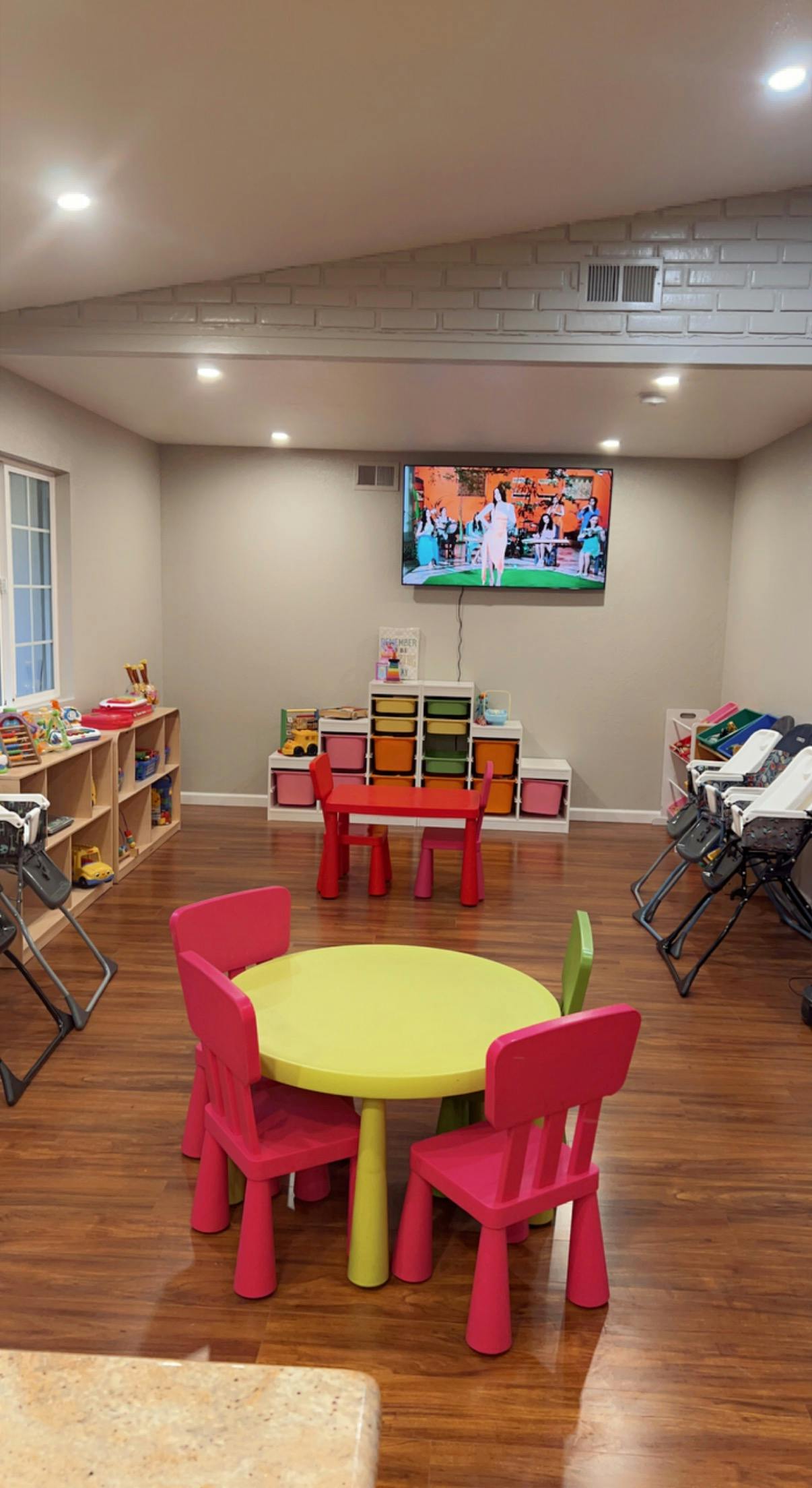 Playroom with small tables and chairs, storage shelves, and high chairs
