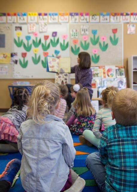 Person reading a book to children in a classroom