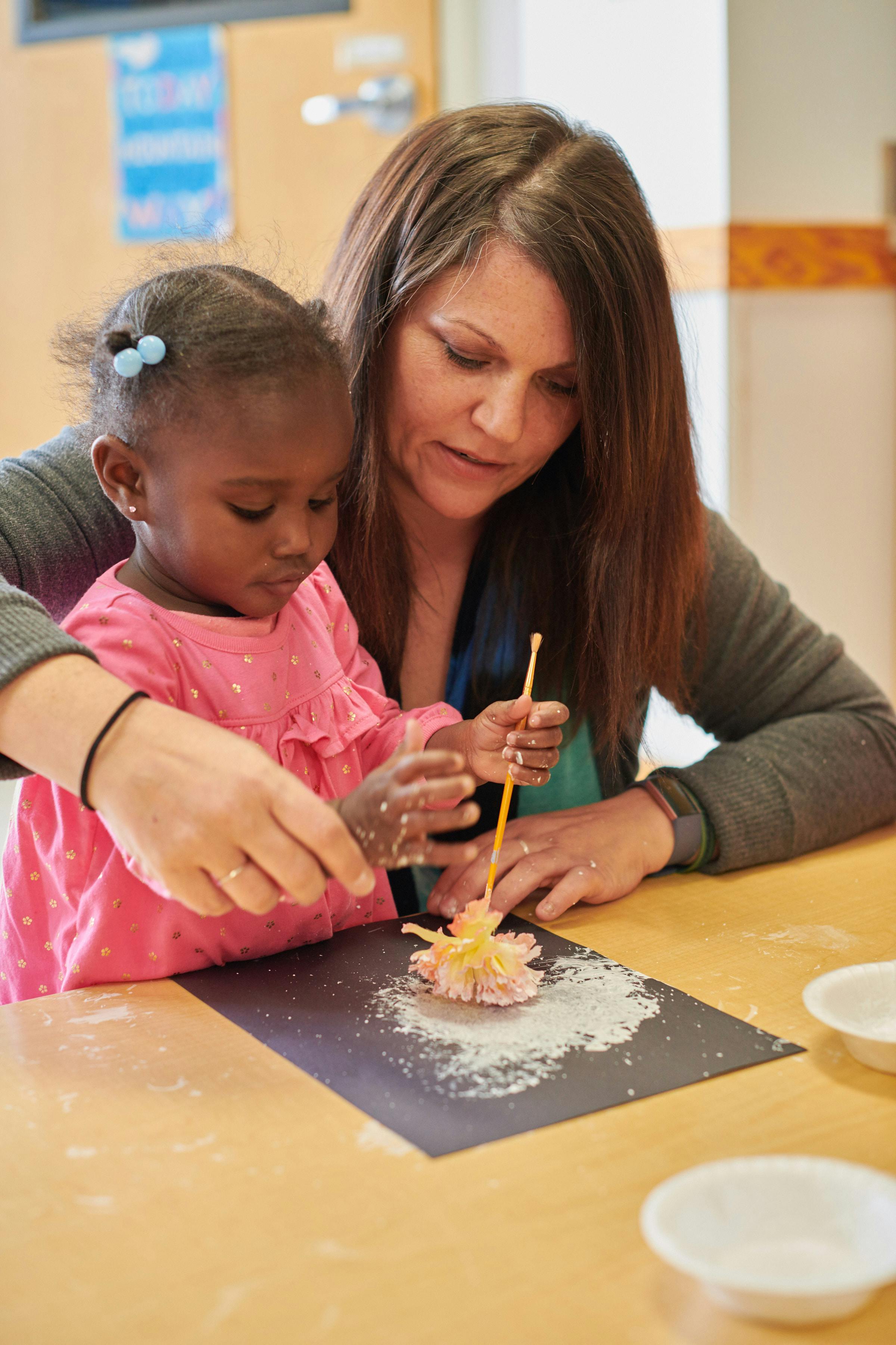 Adult and child doing an art project with glitter