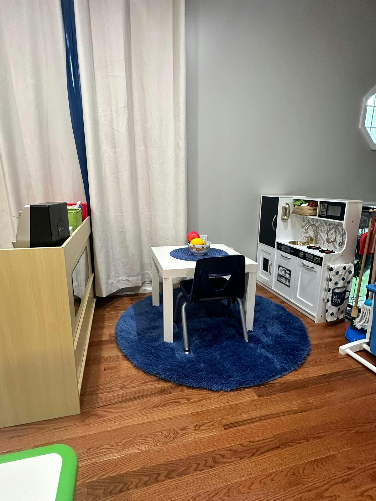 Child's play area with a small table, chair, and toy kitchen
