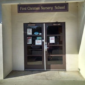 Double doors under a sign that reads "First Christian Nursery School"