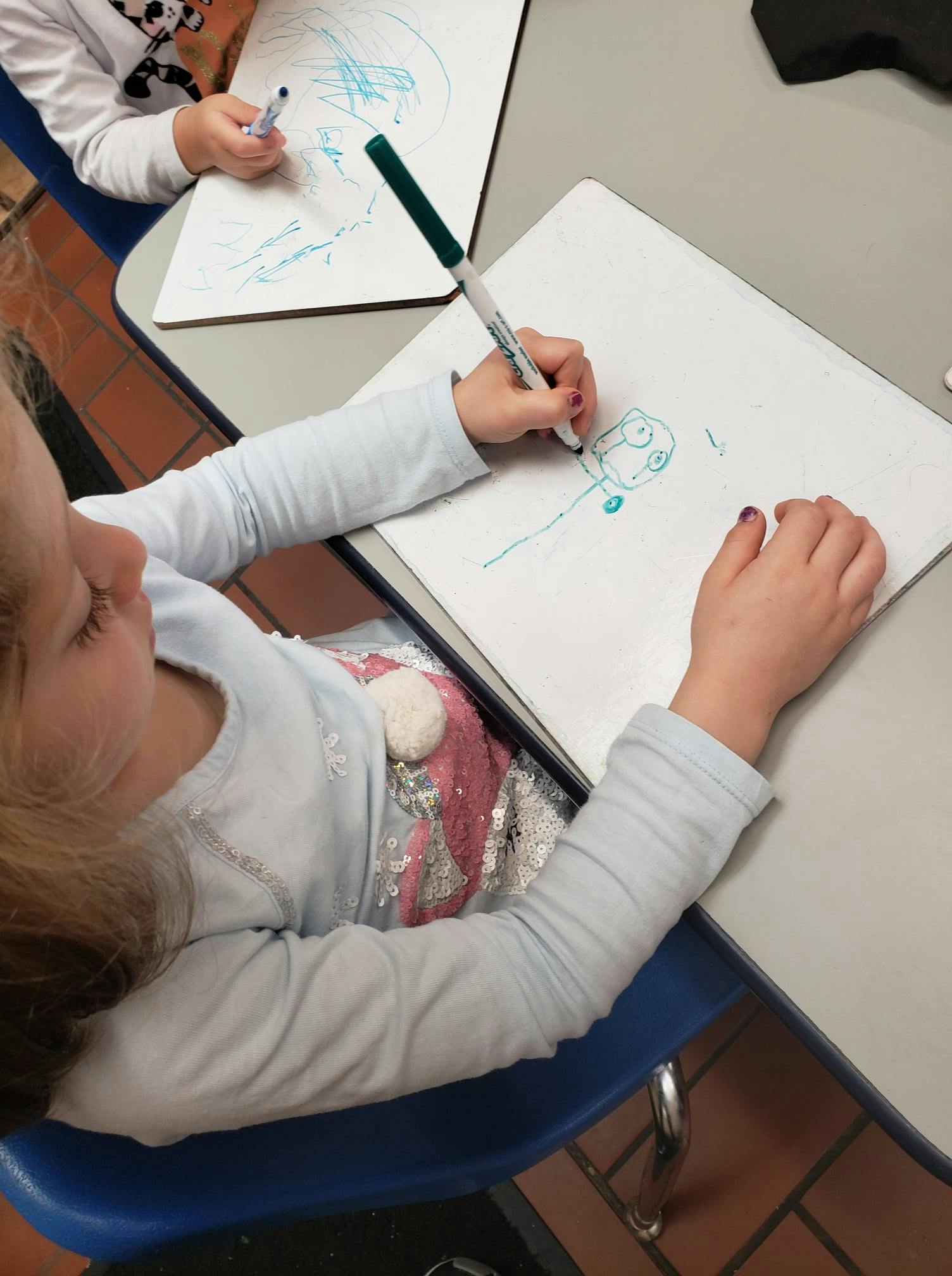 Child drawing on a whiteboard with a marker