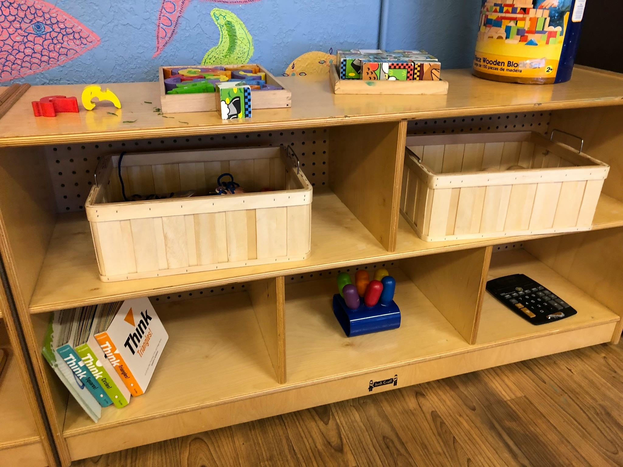Wooden shelving unit with baskets, books, and toys