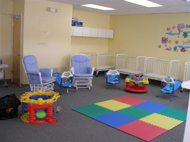 Nursery room with cribs, rocking chairs, and play mats