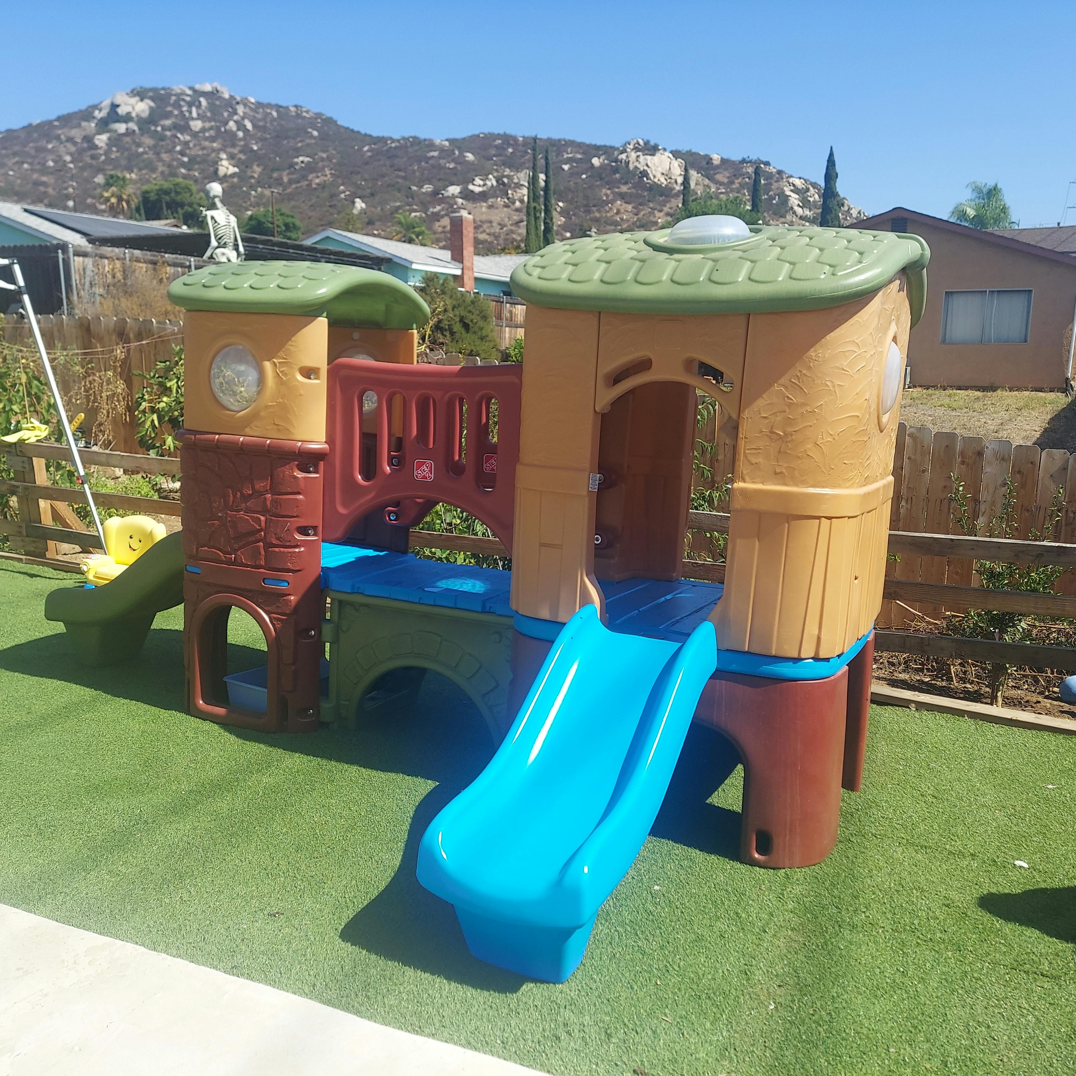 Playground structure with slides on artificial turf
