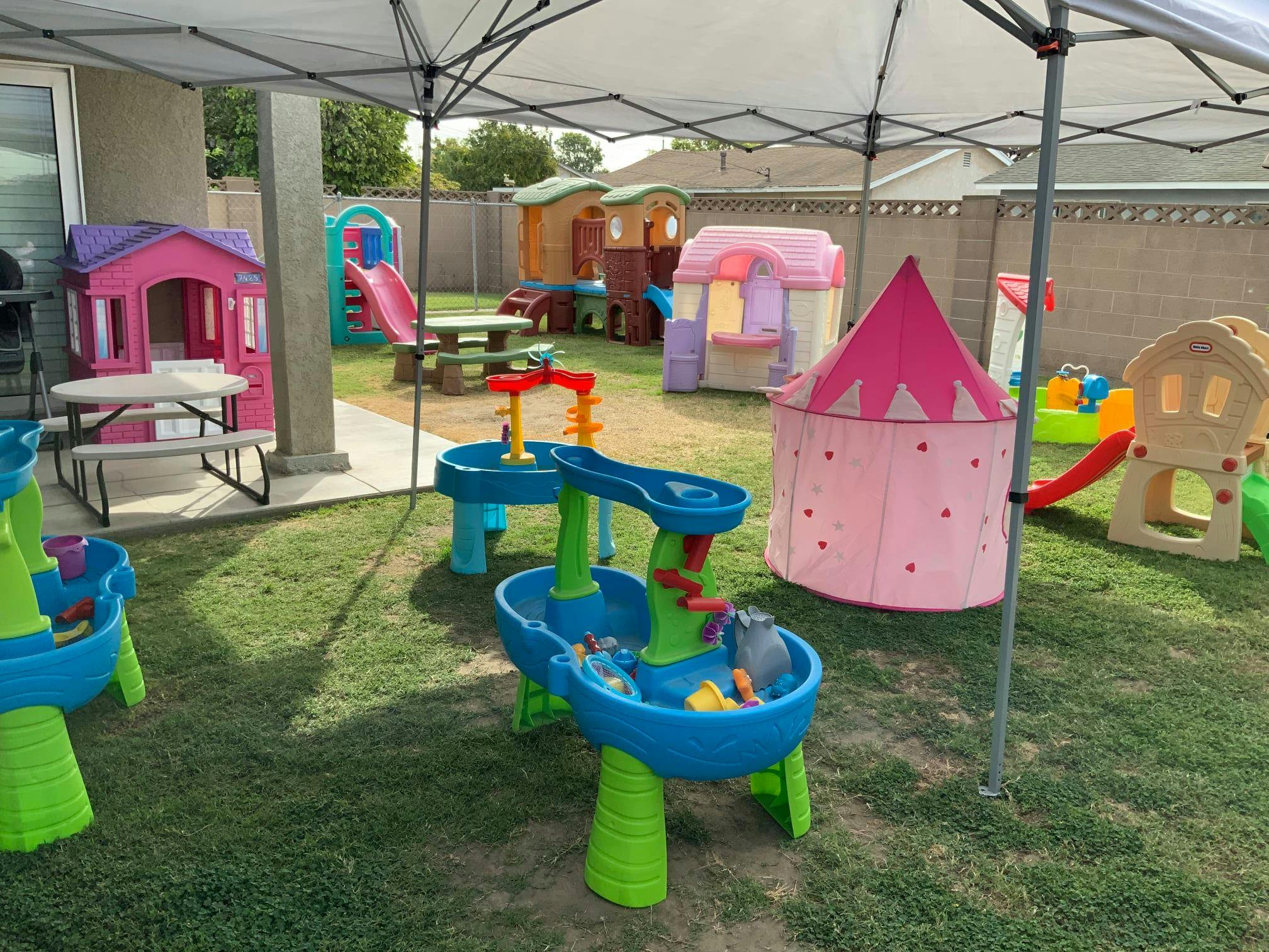 Outdoor play area with various playhouses, slides, and water tables